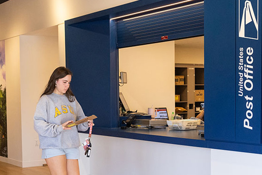 An App State student walking past the University Post Office main window
