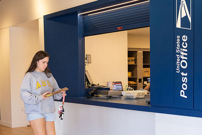 A student walking past the University Post Office main window